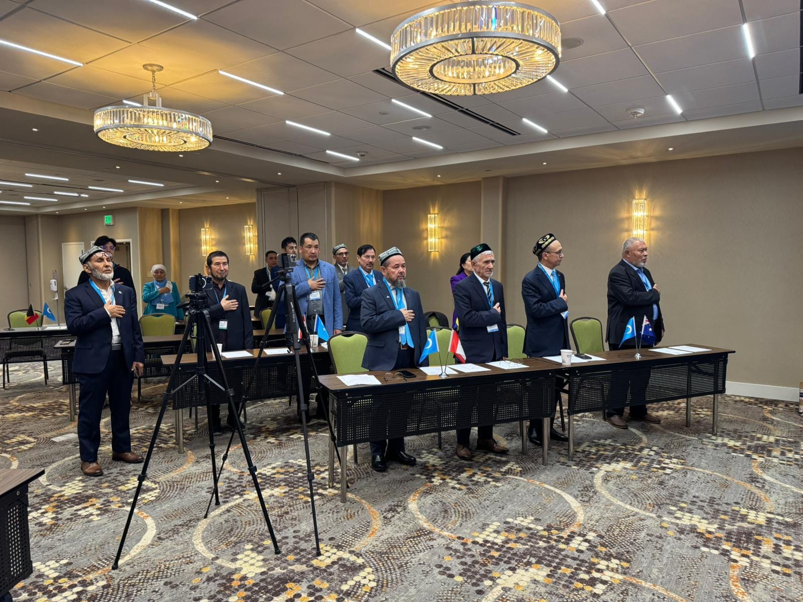 Delegates standing with hands over their hearts at a conference.