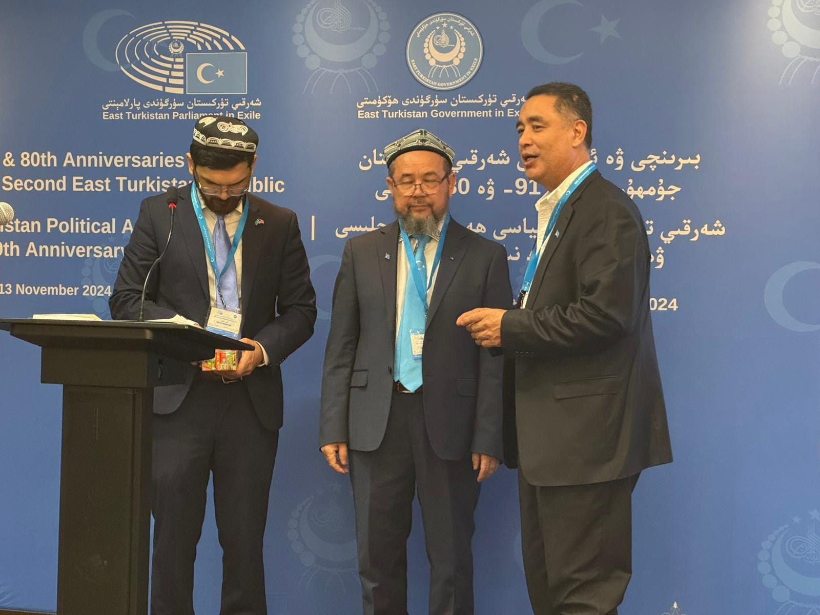 Representatives standing together at the conference podium.