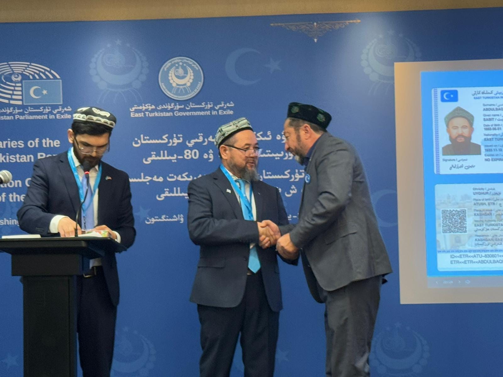 Two men shaking hands at an East Turkistan Government-in-Exile event.