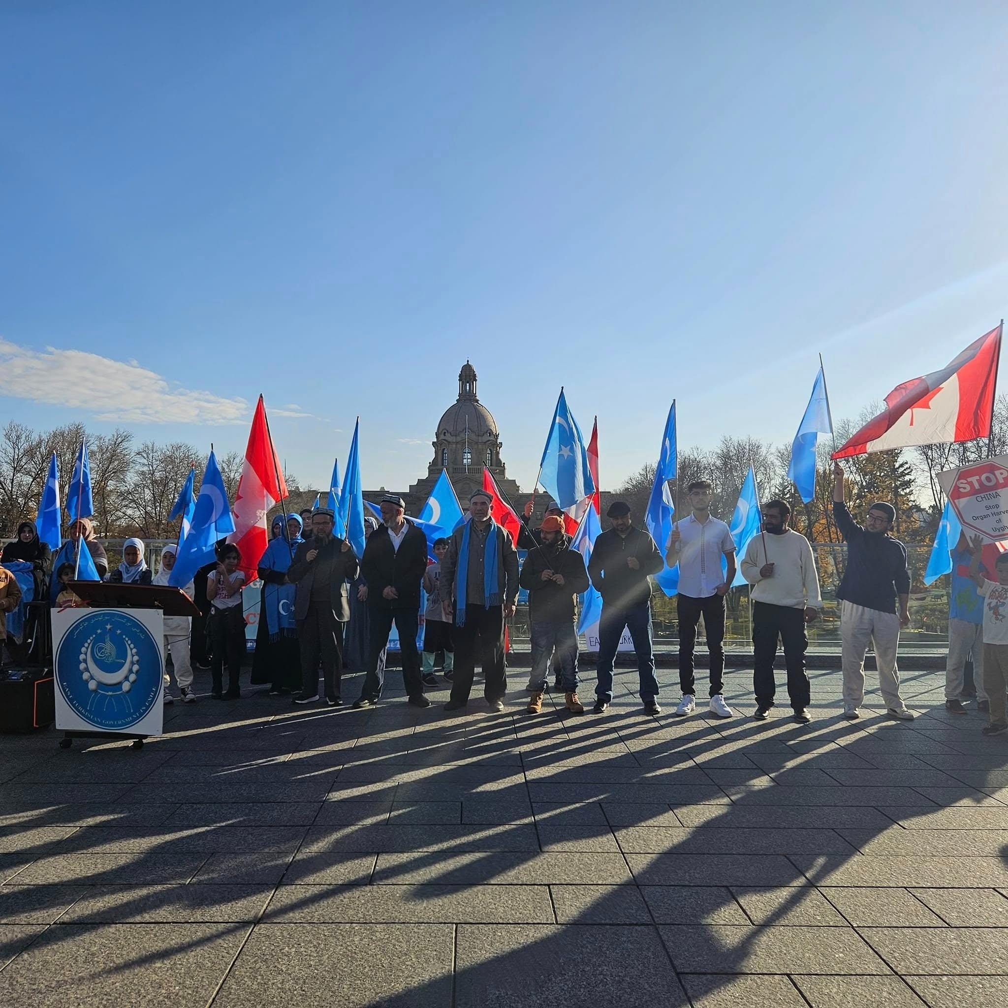 Demonstrators with East Turkistan and Canadian flags in front of the Alberta Legislature.