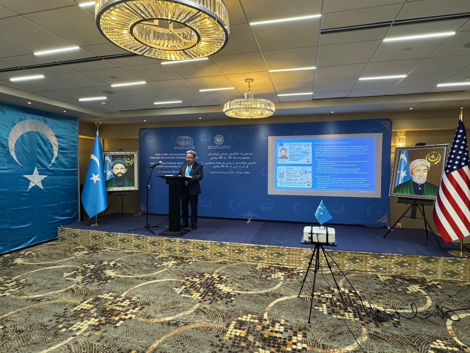 Prime Minister Abdulahad Nur speaking at a podium before East Turkistan Government-in-Exile banners.